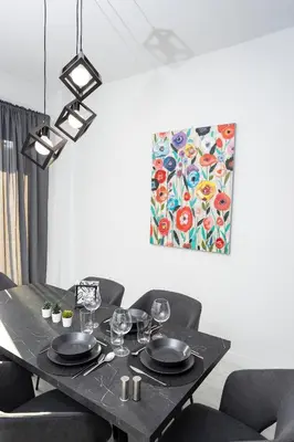 a black table with chairs and a painting on the wall at Bright 2 bedroom apartment in Palaio Faliro in Athens