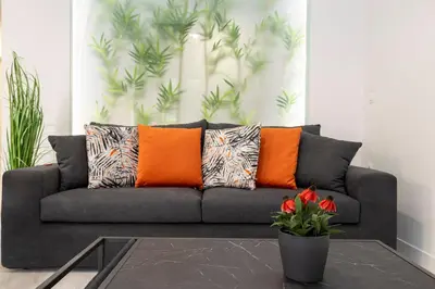 a gray couch with orange pillows in a living room at Bright 2 bedroom apartment in Palaio Faliro in Athens