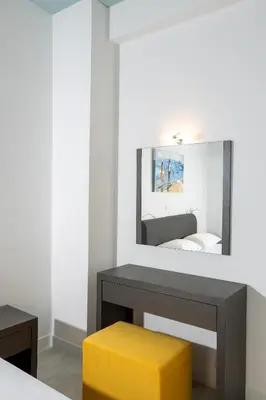 a mirror above a table with a yellow stool at Bright 2 bedroom apartment in Palaio Faliro in Athens