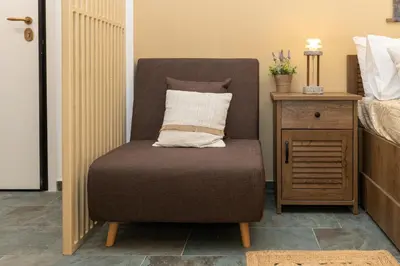 a chair with a pillow on it next to a bed at Hillside Suite Athens in Athens