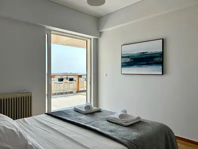 a bedroom with a bed and a large window at Panoramic Penthouse in Athens