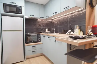 a kitchen with white cabinets and a white refrigerator at The Urban Nest 2 in Athens