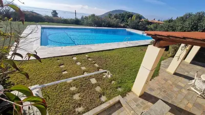 a large swimming pool in a yard with a table at Villa Falmy in Anavissos