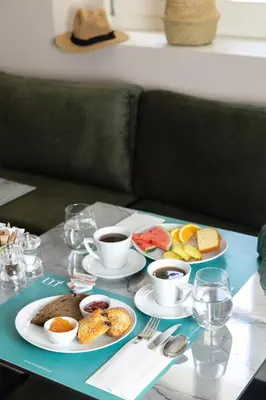 a table with plates of food and cups of coffee at Morus Acropolis Boutique Hotel in Athens