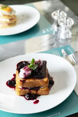 a white plate with a stack of pancakes with blueberry sauce at Morus Acropolis Boutique Hotel in Athens