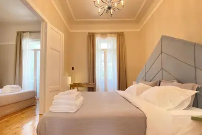 a bedroom with a bed with white sheets and a chandelier at Live in Athens, PANGRATI Fine Residence in Athens