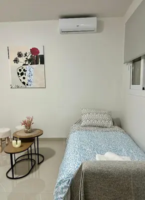 a white bedroom with a bed and a table at Athens Layover Home in Koropíon