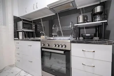 a kitchen with white cabinets and a stove at Central Spot 2-Bedroom Apt by ΜΡS in Athens