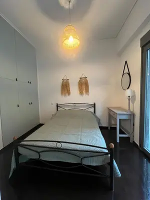 a bedroom with a bed and a table and a lamp at Menta Boho Piraeus Apartment in Piraeus