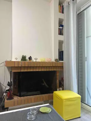 a living room with a fireplace with a yellow stool at Saronida Beachwalk Stay in Saronida