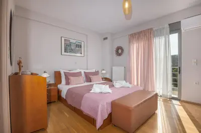 a bedroom with a large bed with a pink bedspread at Villa Anavil - Boutique Coastal Retreat in Varkiza in Vari