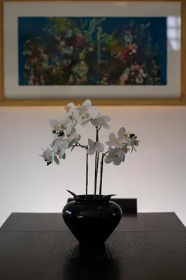 a black vase with white flowers sitting on a table at Villa Anavil - Boutique Coastal Retreat in Varkiza in Vari
