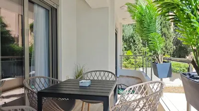 a table and chairs on a balcony with plants at Costa Voula Shared Pool & Beach Apartment A2 in Athens