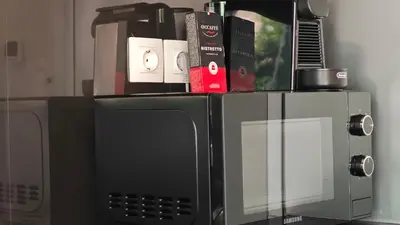 a microwave and a microwave oven with books on top of it at Costa Voula Shared Pool & Beach Apartment A2 in Athens