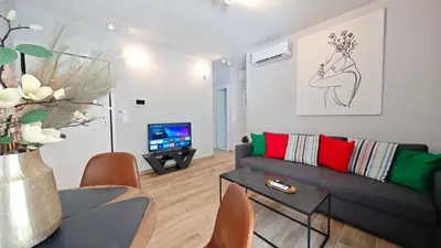 a living room with a couch and a tv at Costa Voula Shared Pool & Beach Apartment A2 in Athens