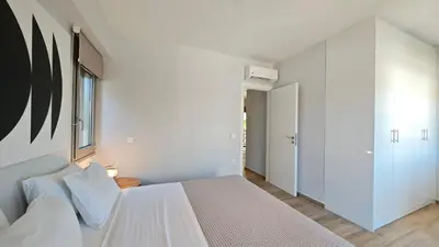 a white bedroom with a bed and a window at Costa Voula Shared Pool & Beach Apartment A2 in Athens