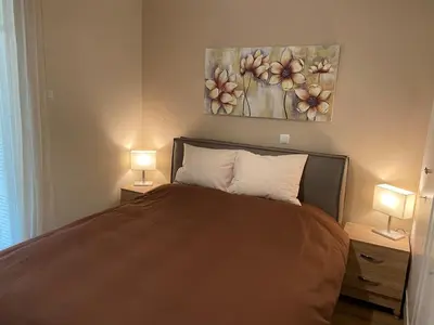 a bedroom with a bed with two lamps and a painting at Cozy Acropolis backyard haven in Athens