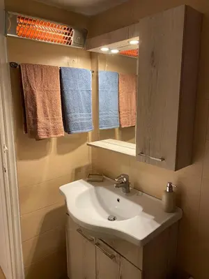 a bathroom with a sink and a mirror and towels at Cozy Acropolis backyard haven in Athens