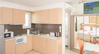 a kitchen with wooden cabinets and a bed in a room at Cozy 6th floor, city center, 30m2, sun terrace in Athens