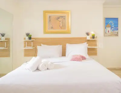 a bedroom with a white bed with towels on it at Cozy 6th floor, city center, 30m2, sun terrace in Athens