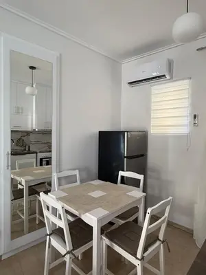 a dining room with a table and chairs and a refrigerator at Andys house in Athens