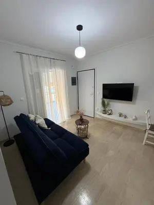 a living room with a blue couch and a tv at Andys house in Athens