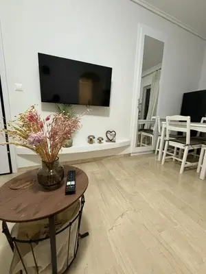 a living room with a table and a tv on a wall at Andys house in Athens