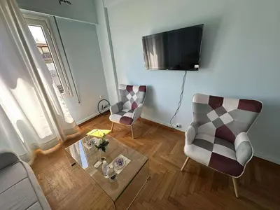a living room with two chairs and a television at The Athenian Spot in Athens