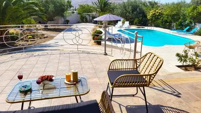 a patio with two chairs and a table next to a pool at Luxury villa Espera Lagonisi with private pool in Kalívia Thorikoú