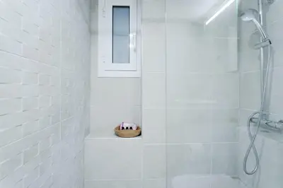 a white bathroom with a shower and a basket at Sefis apartment in Athens