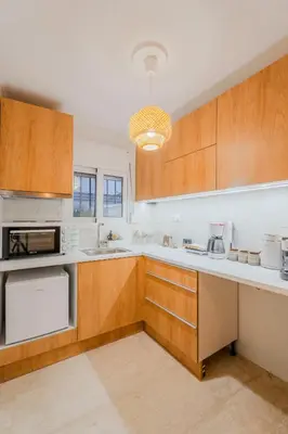 a kitchen with white counters and wooden cabinets at Sefis apartment in Athens