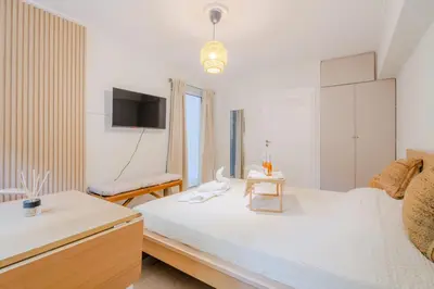 a white bedroom with a bed and a tv at Sefis apartment in Athens