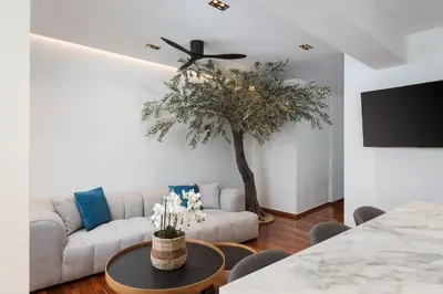 a living room with a couch and a tree at Glyfada Lux Olive Suites - Aura & Glow in Athens