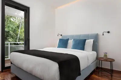 a bedroom with a large white bed with blue pillows at Glyfada Lux Olive Suites - Aura & Glow in Athens