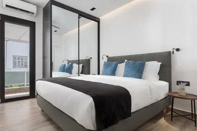 a bedroom with a large bed with blue pillows at Glyfada Lux Olive Suites - Aura & Glow in Athens