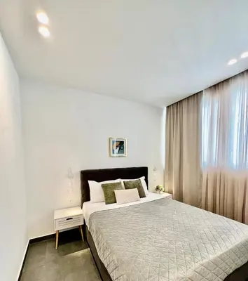 a white bedroom with a large bed and a window at Home in Piraeus in Piraeus