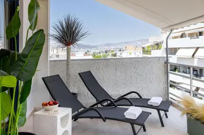 a patio with chairs and a palm tree on a balcony at Pause In Athens in Athens
