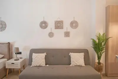 a living room with a couch and a white wall at Silia Spotless Fully Renovated Studio in Athens
