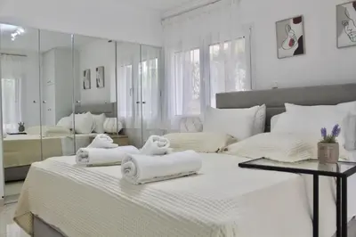 a white bedroom with two towels on a bed at Luxury varkiza apartment in Vari
