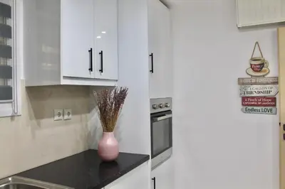 a kitchen with white cabinets and a vase on a counter at Luxury varkiza apartment in Vari