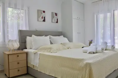 a white bedroom with a large bed with white pillows at Luxury varkiza apartment in Vari