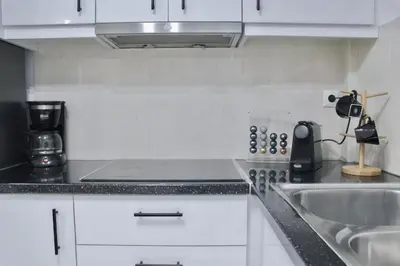 a kitchen with white cabinets and a sink at Luxury varkiza apartment in Vari