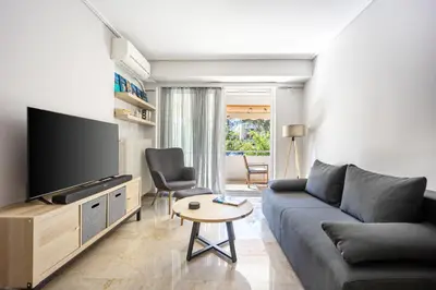 a living room with a couch and a tv at Glyfada Muse - Sea and City Apartment in Athens
