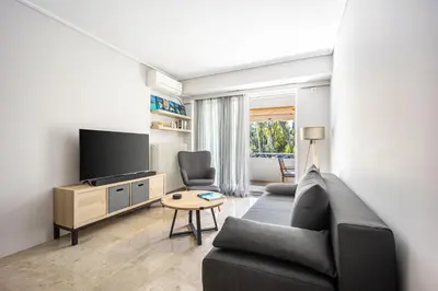 a living room with a couch and a tv at Glyfada Muse - Sea and City Apartment in Athens