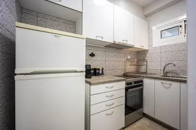 a kitchen with white cabinets and a refrigerator at Glyfada Muse - Sea and City Apartment in Athens