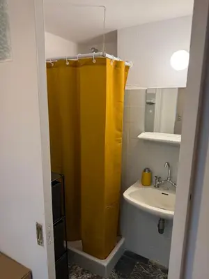 a bathroom with a yellow shower curtain and a sink at Sunshine Apartment in Palaiá Fókaia