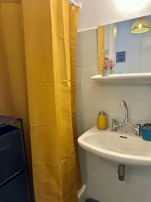 a bathroom with a sink and a yellow shower curtain at Sunshine Apartment in Palaiá Fókaia