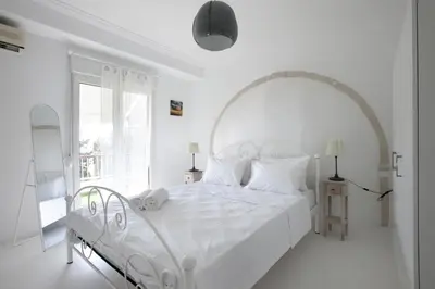 a white bedroom with a white bed and a window at Ano Patisia, A 5th Floor Fully Renovated Penthouse in Athens