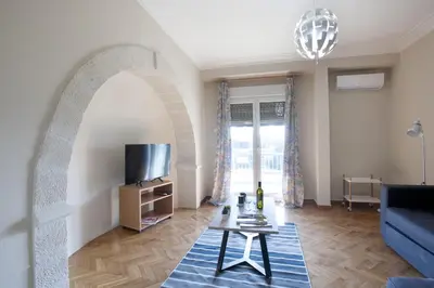 a living room with a blue couch and a tv at Ano Patisia, A 5th Floor Fully Renovated Penthouse in Athens