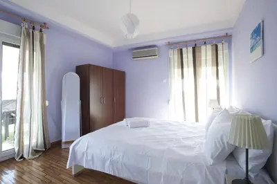 a bedroom with a white bed and a large window at Ano Patisia, A 5th Floor Fully Renovated Penthouse in Athens